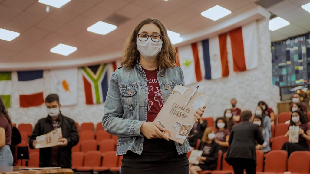 Formanda da Escola de Missão recebendo certificado.